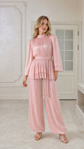 Front view of woman wearing blush pink pleated tunic top and matching trousers set
