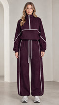 Front view of woman wearing burgundy quarter-zip tracksuit set with white contrast piping