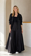 Front full view of woman wearing Black contrast stitch maxi duster coat and wide-leg trousers