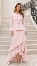 Front full view of pink ruffled two-piece maxi dress set on model standing on staircase