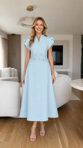 Front view of model wearing light blue A-line midi dress with beaded floral waist