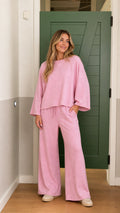 Front full-body view of model wearing pink relaxed crewneck sweatshirt and wide-leg pants set