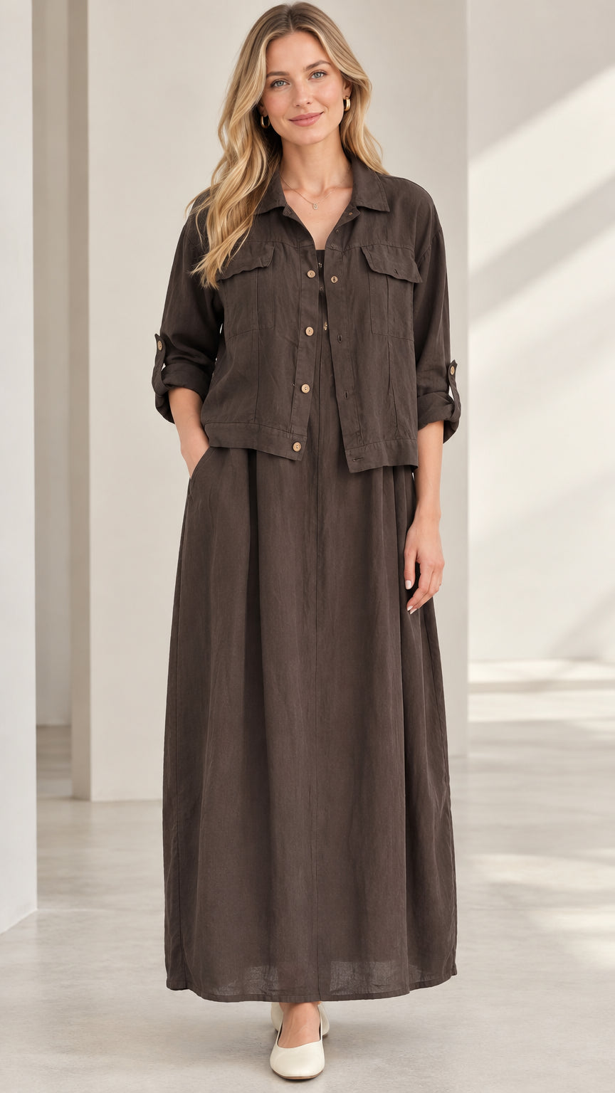 Front view of model wearing dark brown collared shirt jacket and matching pleated maxi skirt set