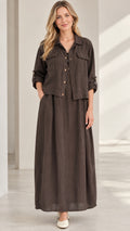 Front view of model wearing dark brown collared shirt jacket and matching pleated maxi skirt set
