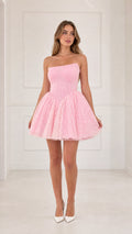Front view of model wearing pink strapless basque waist lace mini dress with white heels