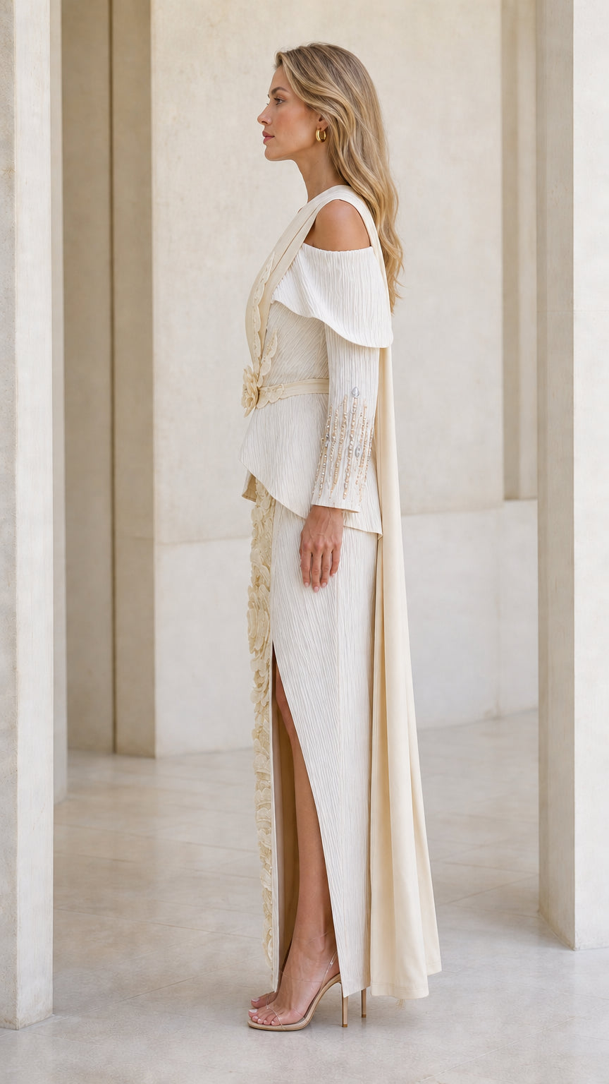 Side profile view of champagne evening gown showing cascading shoulder sash and slit