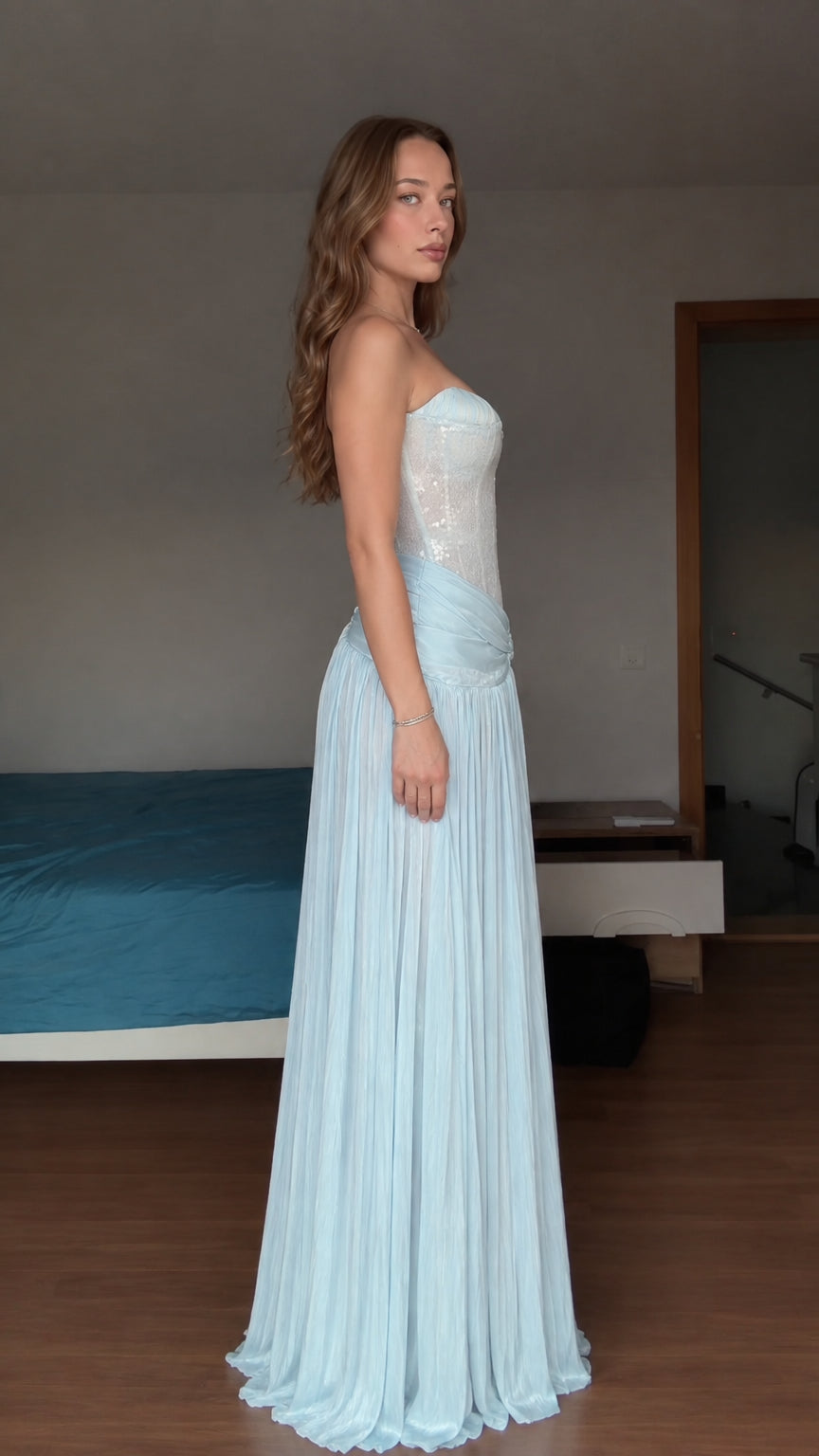 Side profile view of model wearing light blue strapless pleated formal maxi dress