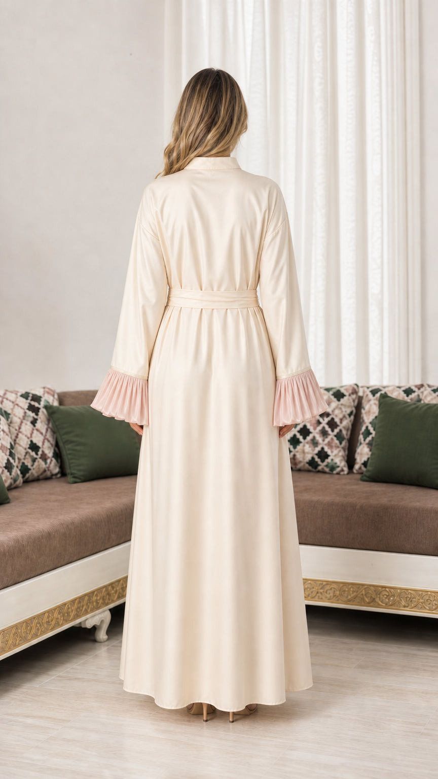 Back view of woman wearing cream floor-length abaya with tie sash
