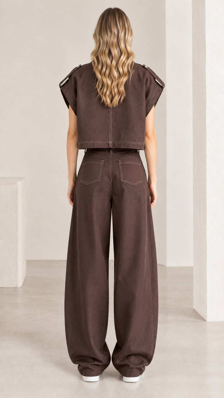 Back view of woman wearing chocolate brown cropped shirt and relaxed wide-leg trousers