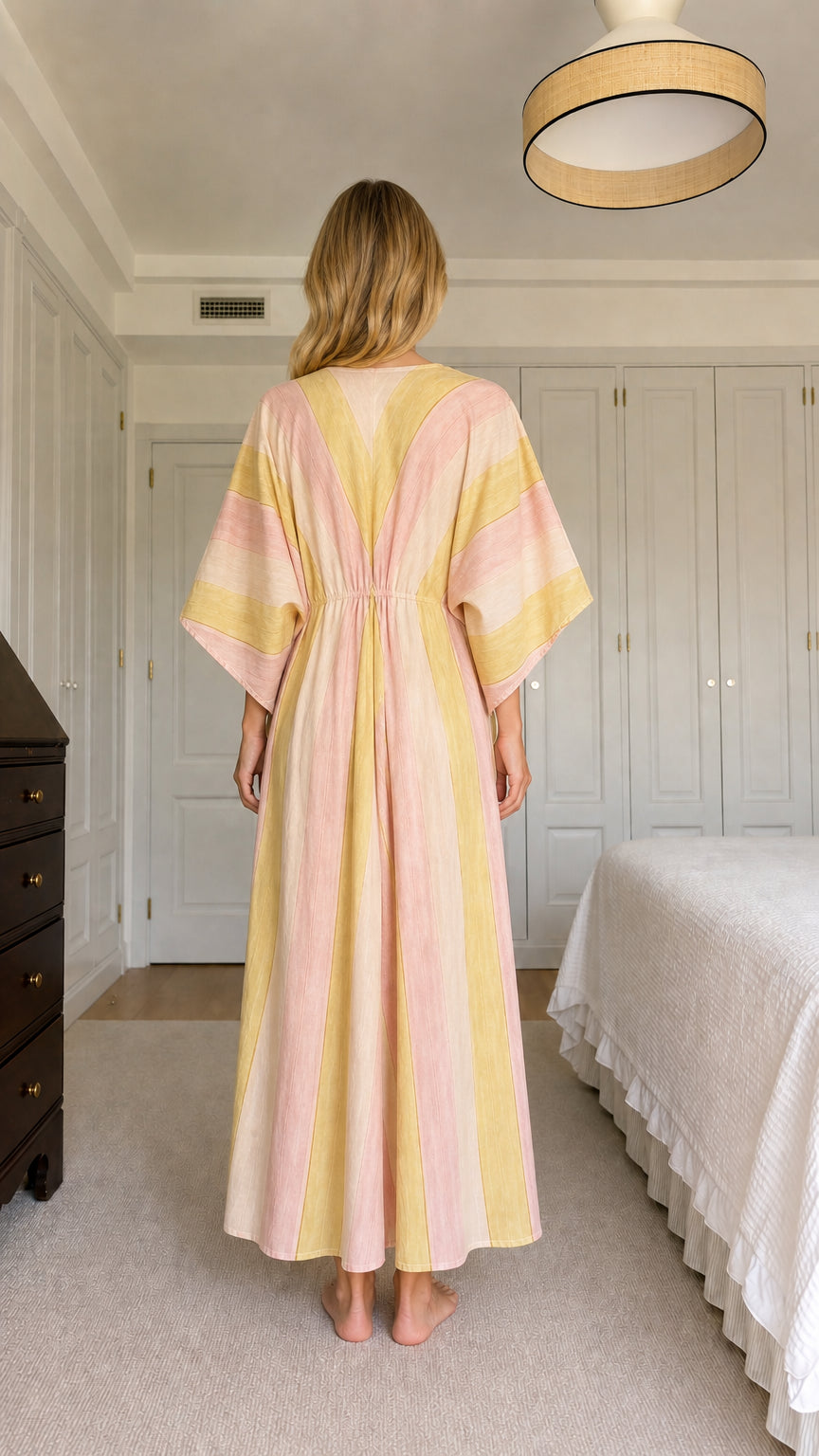 Back view of model wearing pink and yellow striped maxi kaftan dress