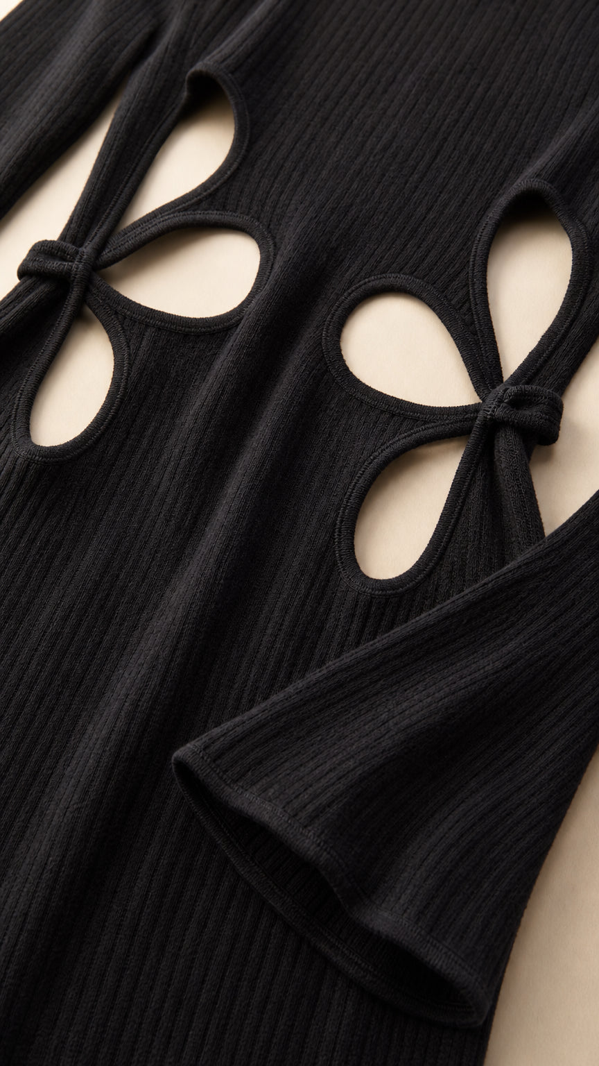 Close-up detail of black ribbed fabric showing petal waist cutouts and sleeve cuff