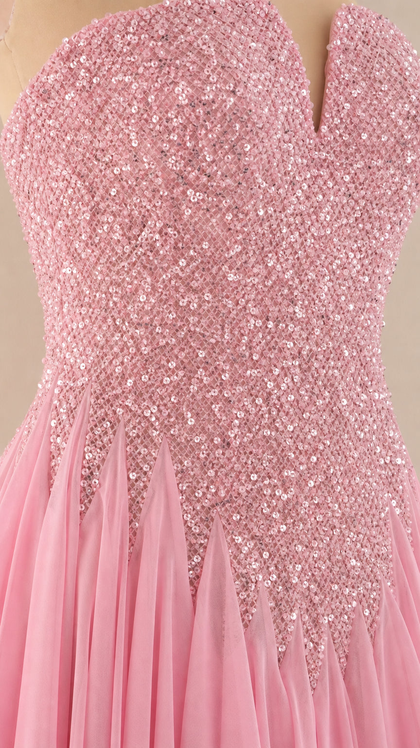 Close-up detail of pink sequin embellishment and accordion pleated skirt seam