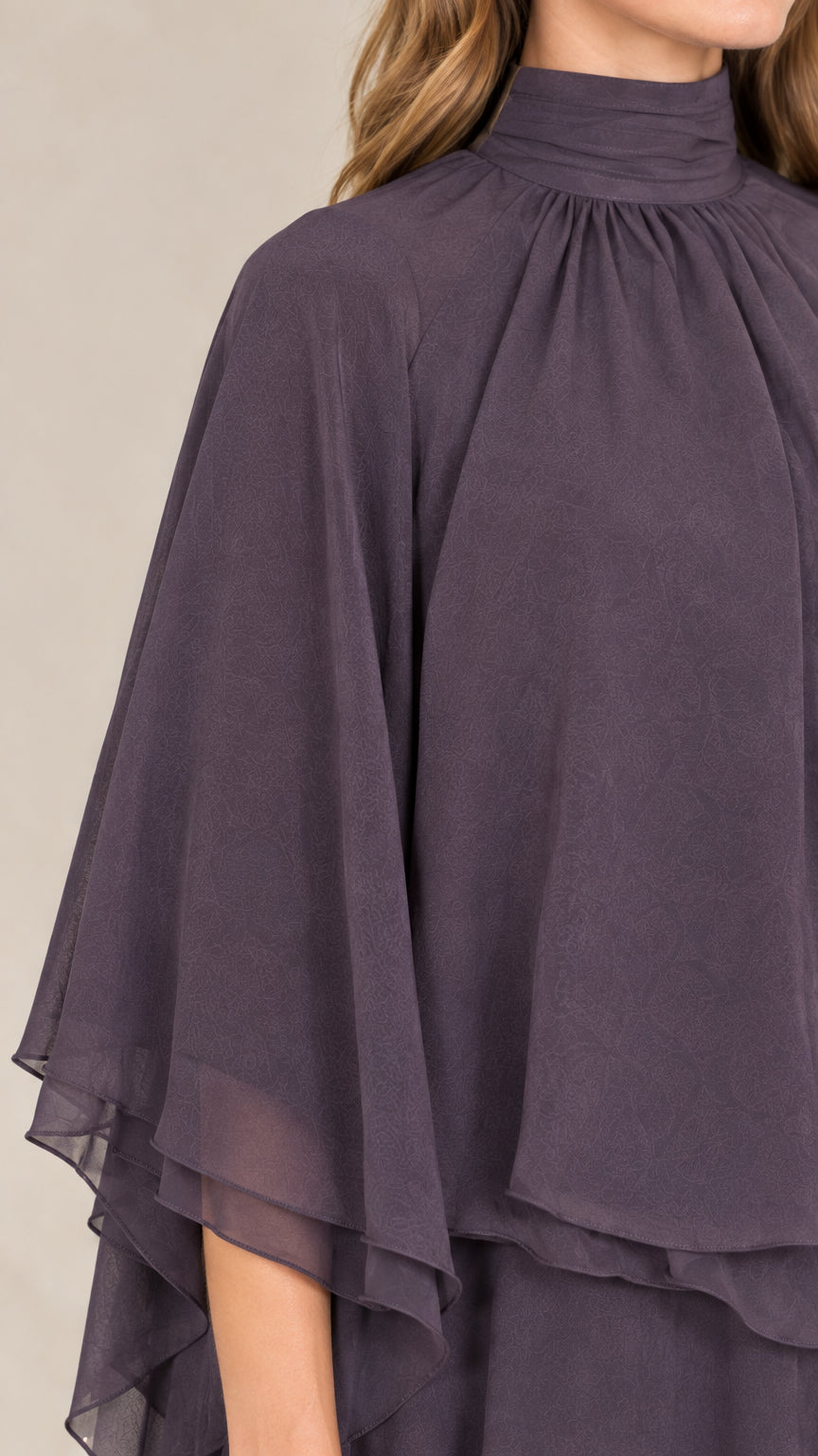 Close-up detail of gathered mock neckline and layered capelet sleeve