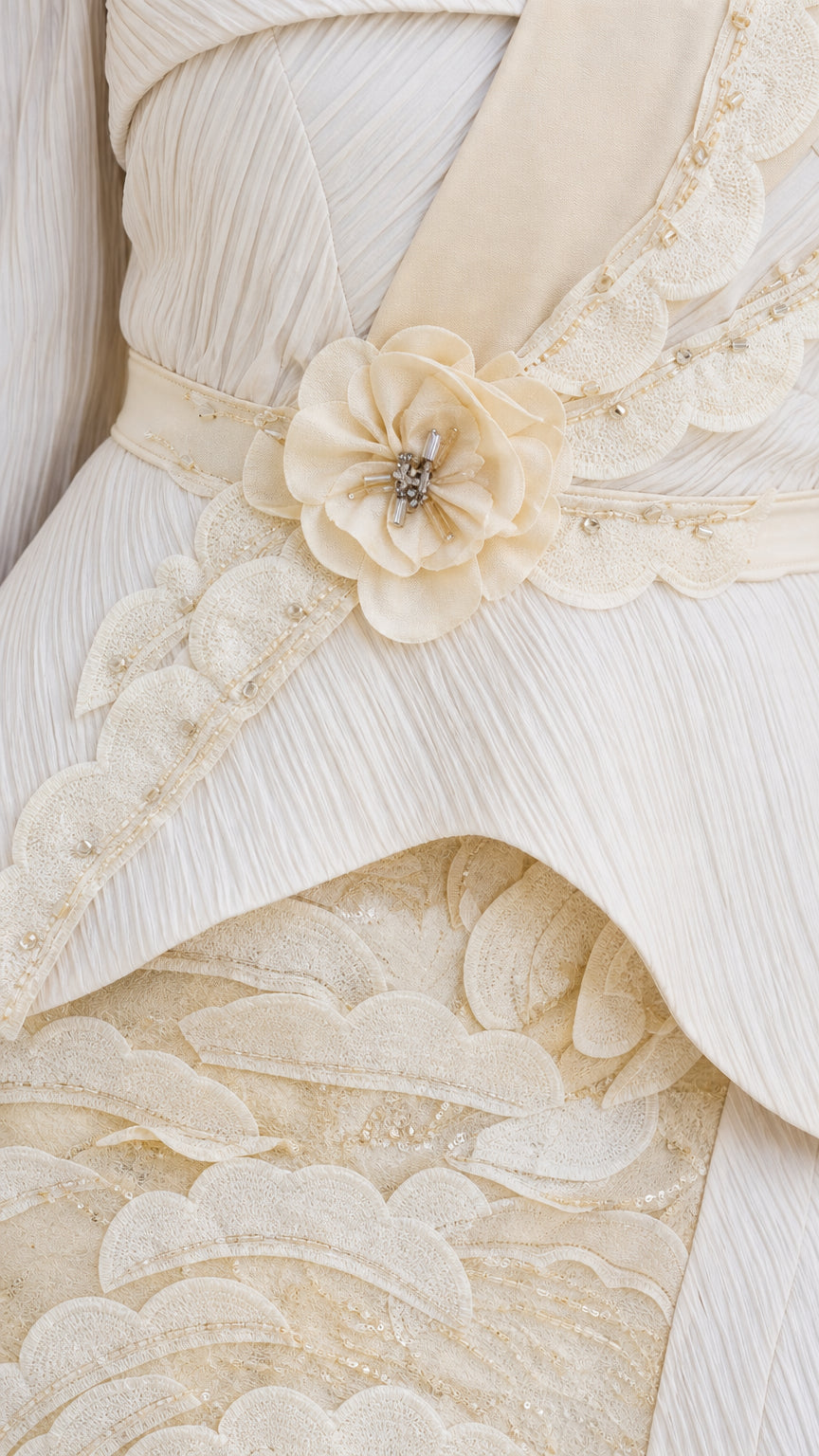 Close-up detail of floral waist applique and pleated bodice on champagne dress