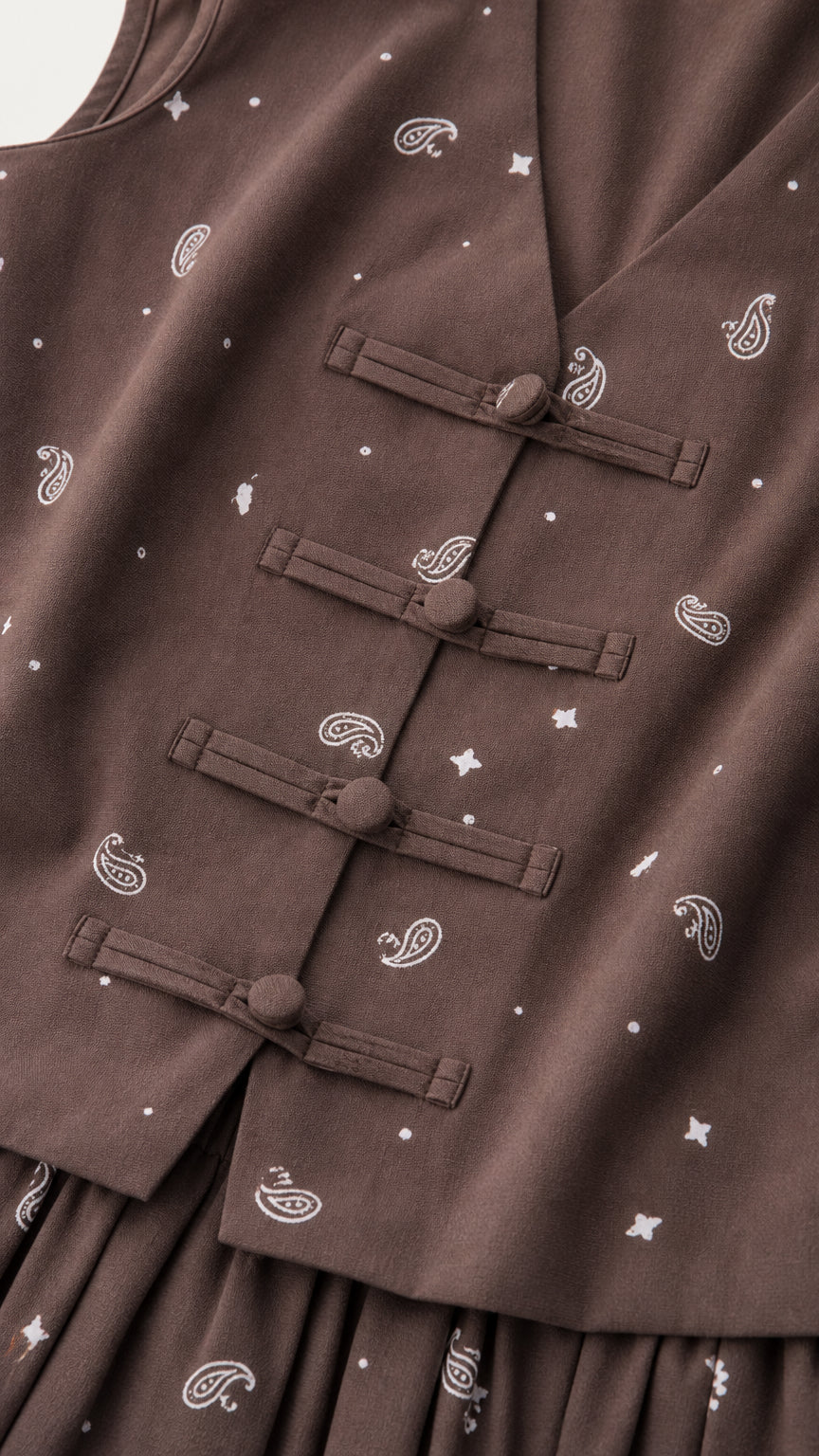 Close-up of brown vest with knot buttons and print